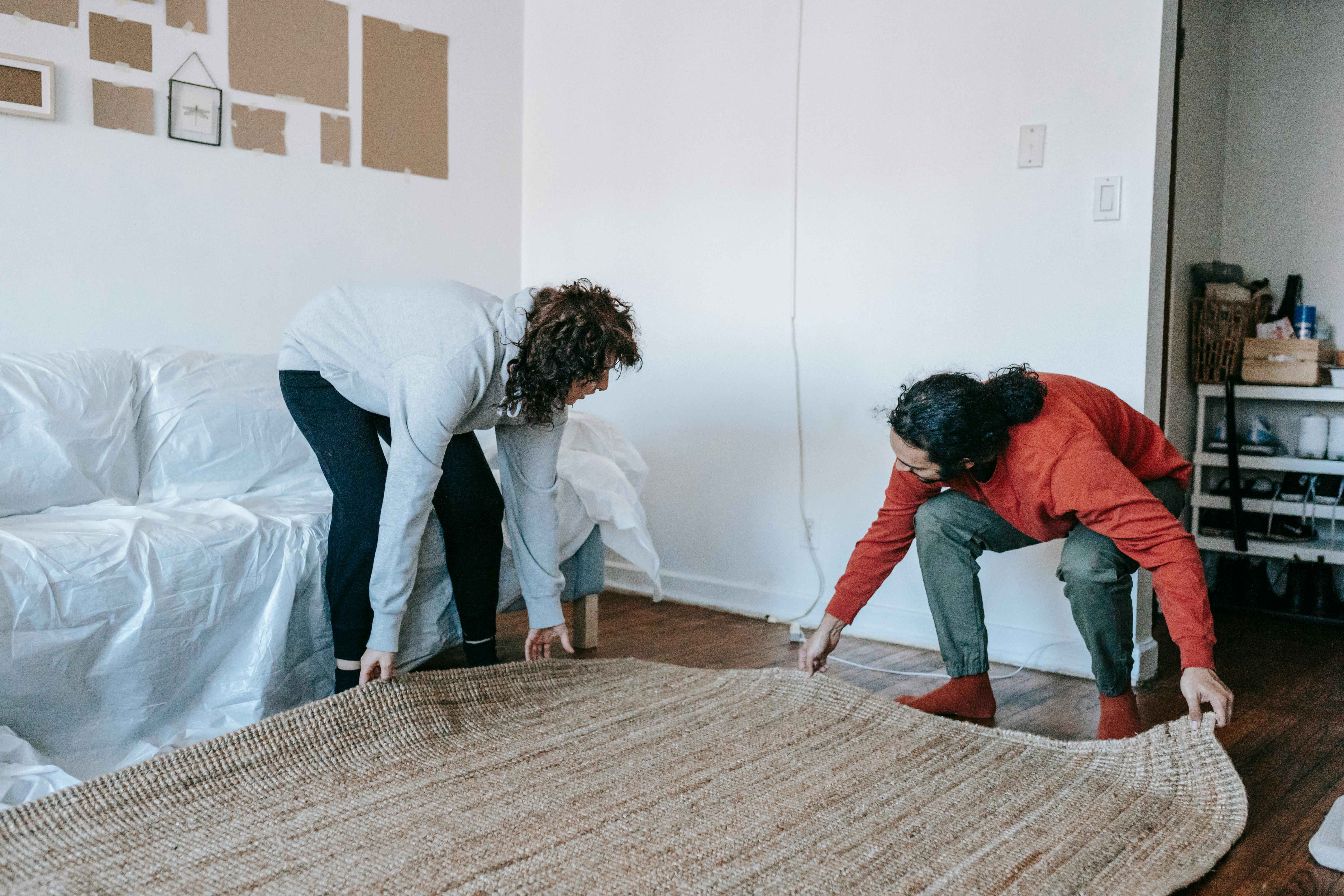 Two people laying down a rug